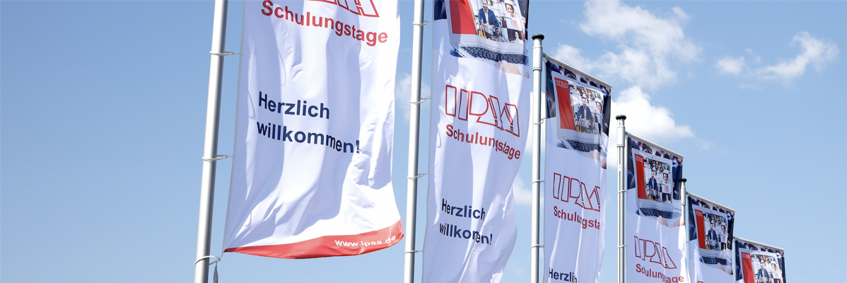 IPAA-Fahnen im Wind vor strahlend blauem Himmel