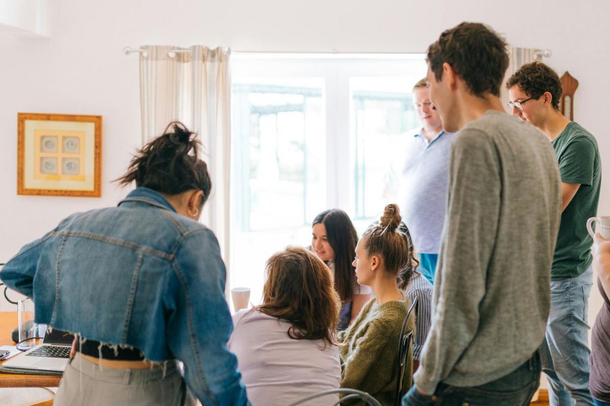 Fünf Personen, Die In Der Nähe Von Vier Personen Stehen, Die In Der Nähe Des Schreibtisches Sitzen