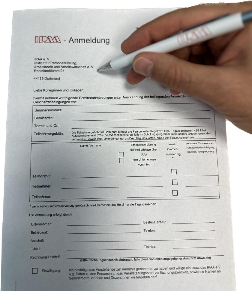 Eine Hand die mit einem Kugelschreiber ein IPAA-Anmeldeformular ausfüllt