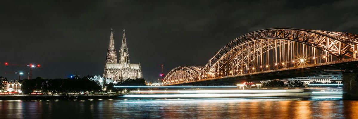 Wunderschöne nächtliche Langzeitbelichtung des Kölner Doms und der Hohenzollernbrücke, die sich im Rhein spiegeln.